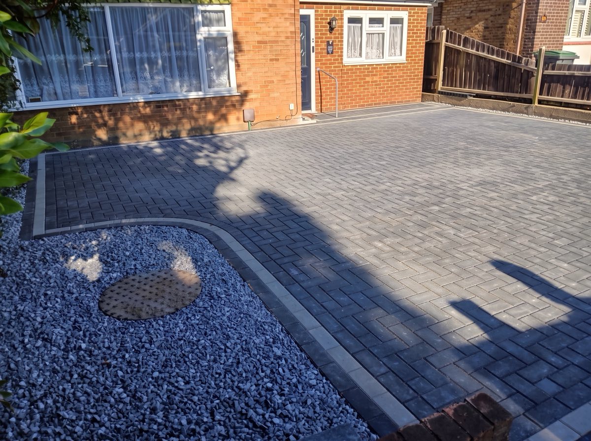 Grey block-paved driveway with a contrasting border and decorative gravel bed