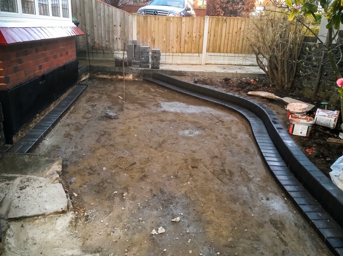 Cleared side garden with new curved block edging before paving