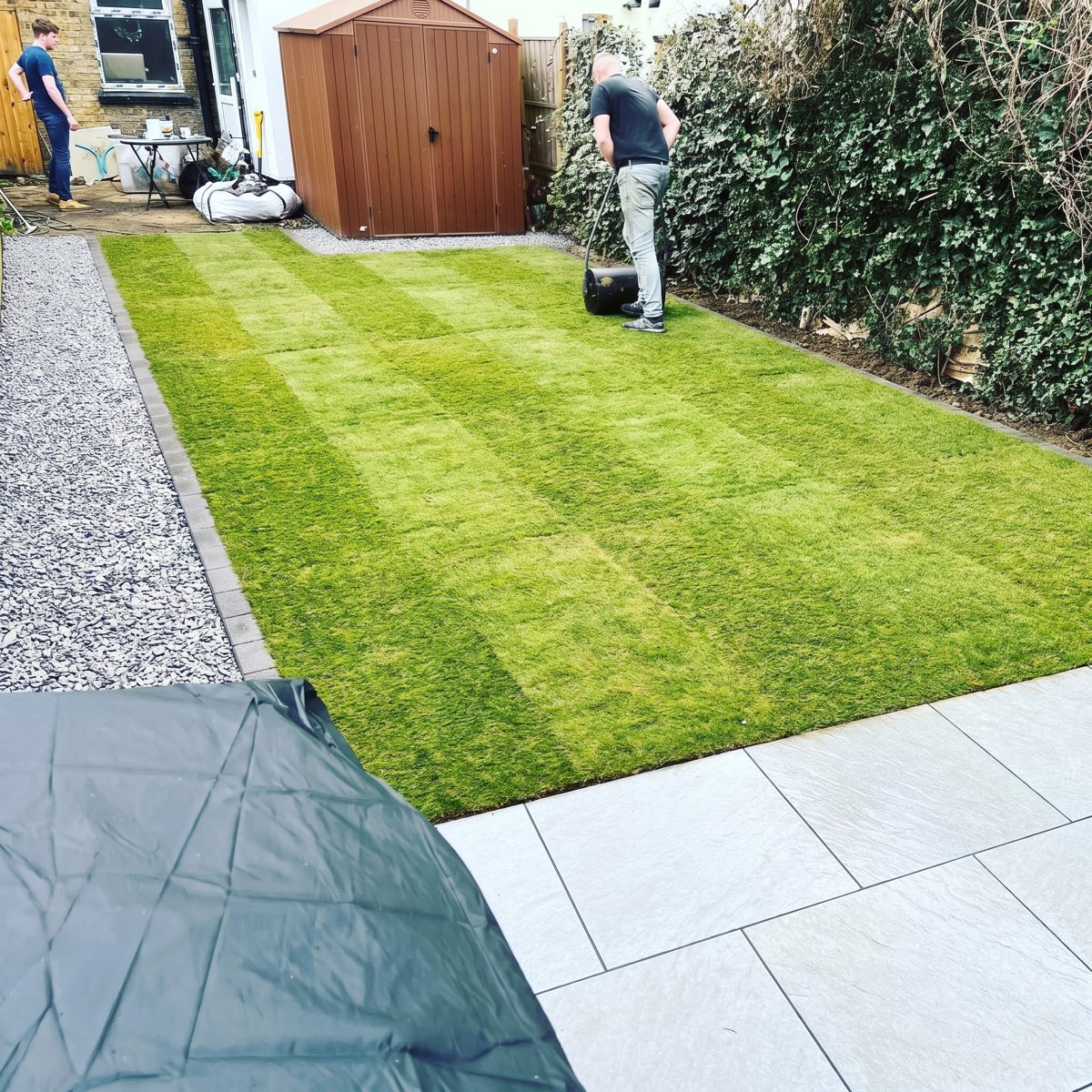Back garden after: new striped turf with block edging, gravel walkway and porcelain patio