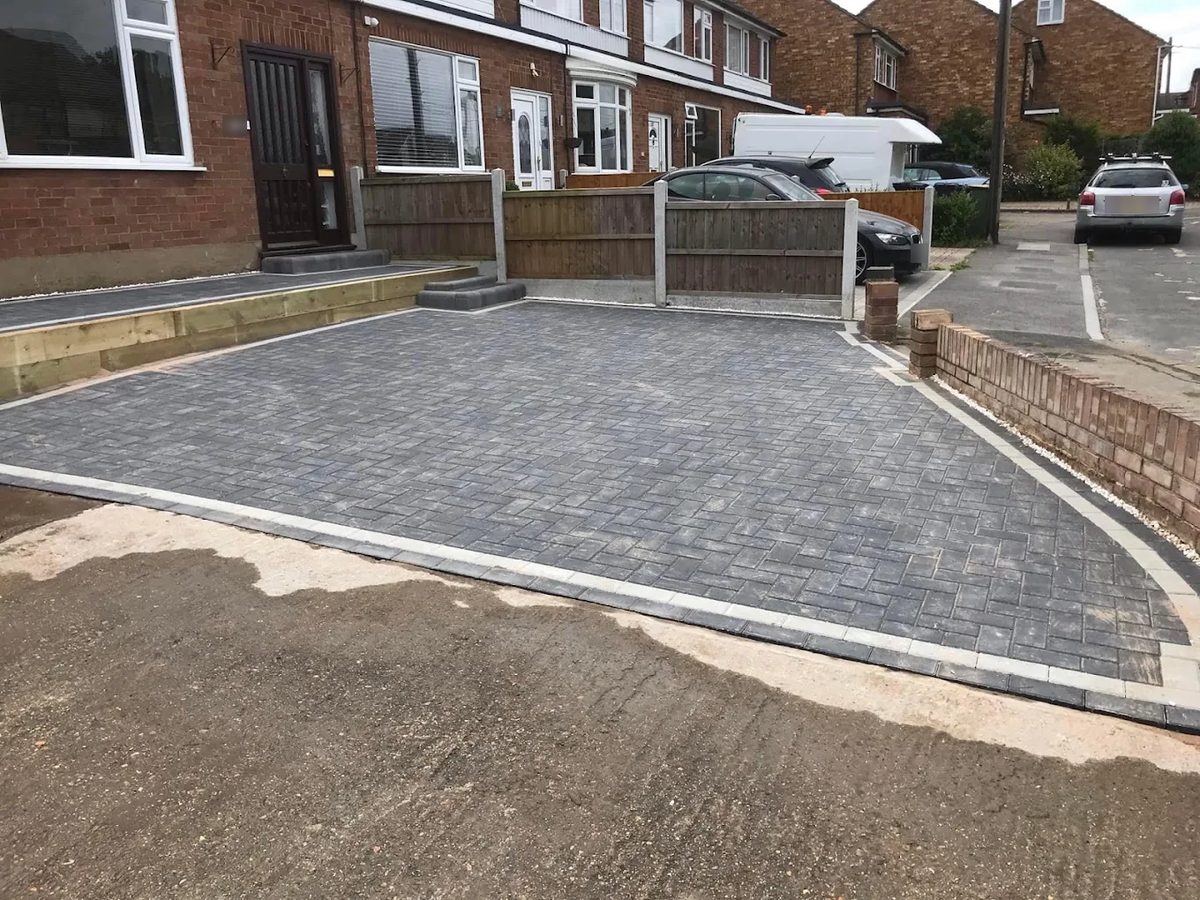Charcoal herringbone block driveway with silver borders and a raised sleeper-edged path
