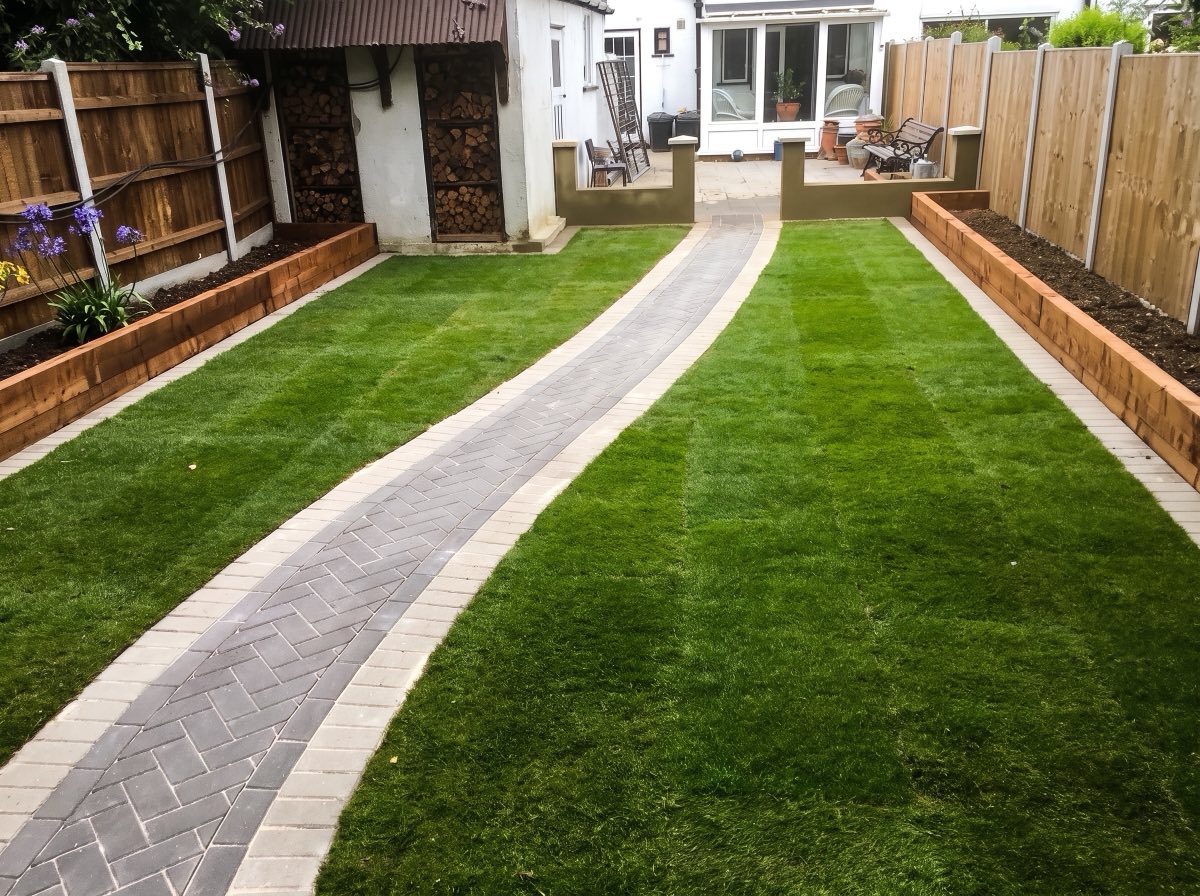 Herringbone block path running through a new striped lawn with sleeper beds