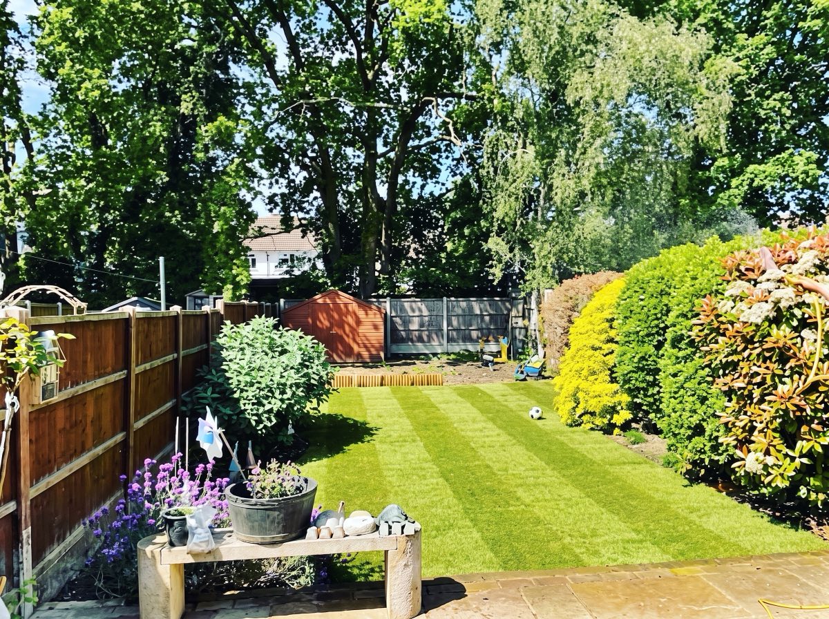 Finished striped lawn with borders and a stone bench