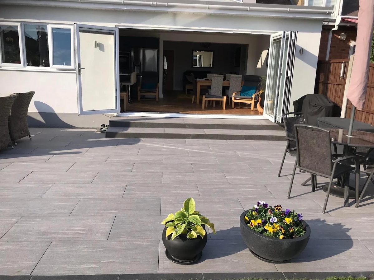 Light grey porcelain patio with wide steps up to open bi-fold doors