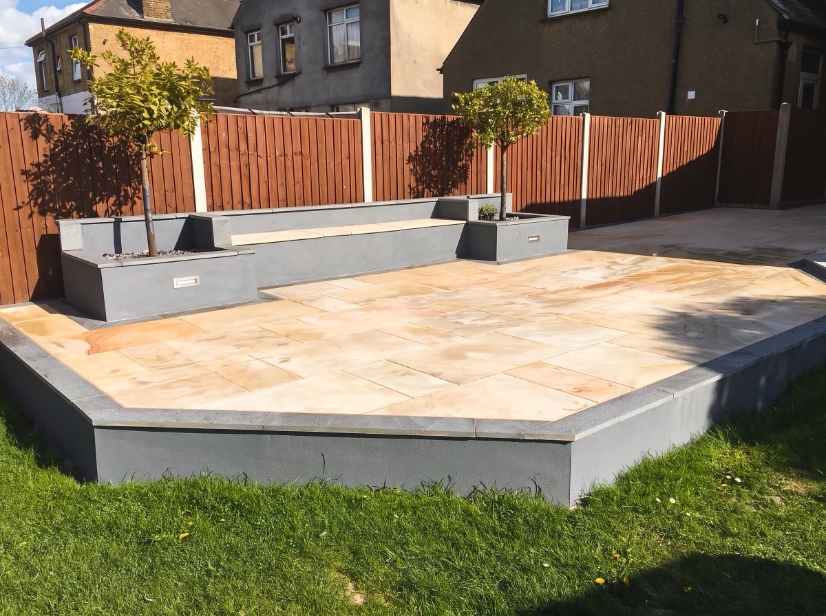 Sandstone patio with grey rendered raised planters and a built-in bench