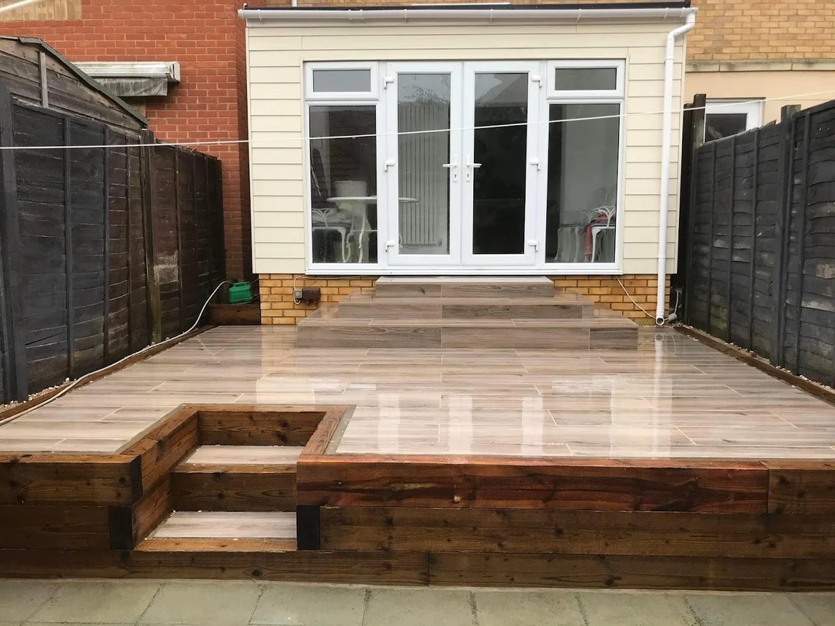 Raised wood-effect porcelain patio with sleeper retaining walls and steps